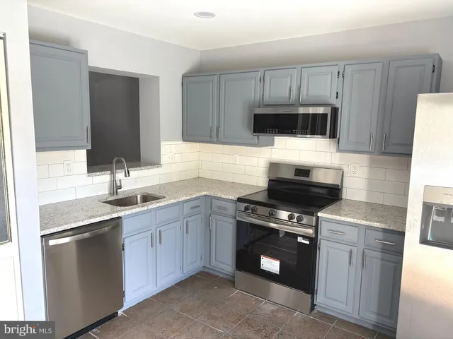 a kitchen with granite countertop a sink stainless steel appliances and cabinets