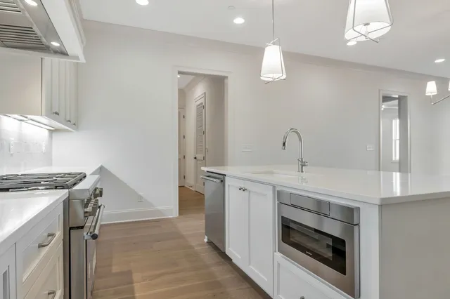 a kitchen with kitchen island stainless steel appliances a chandelier and wooden floors