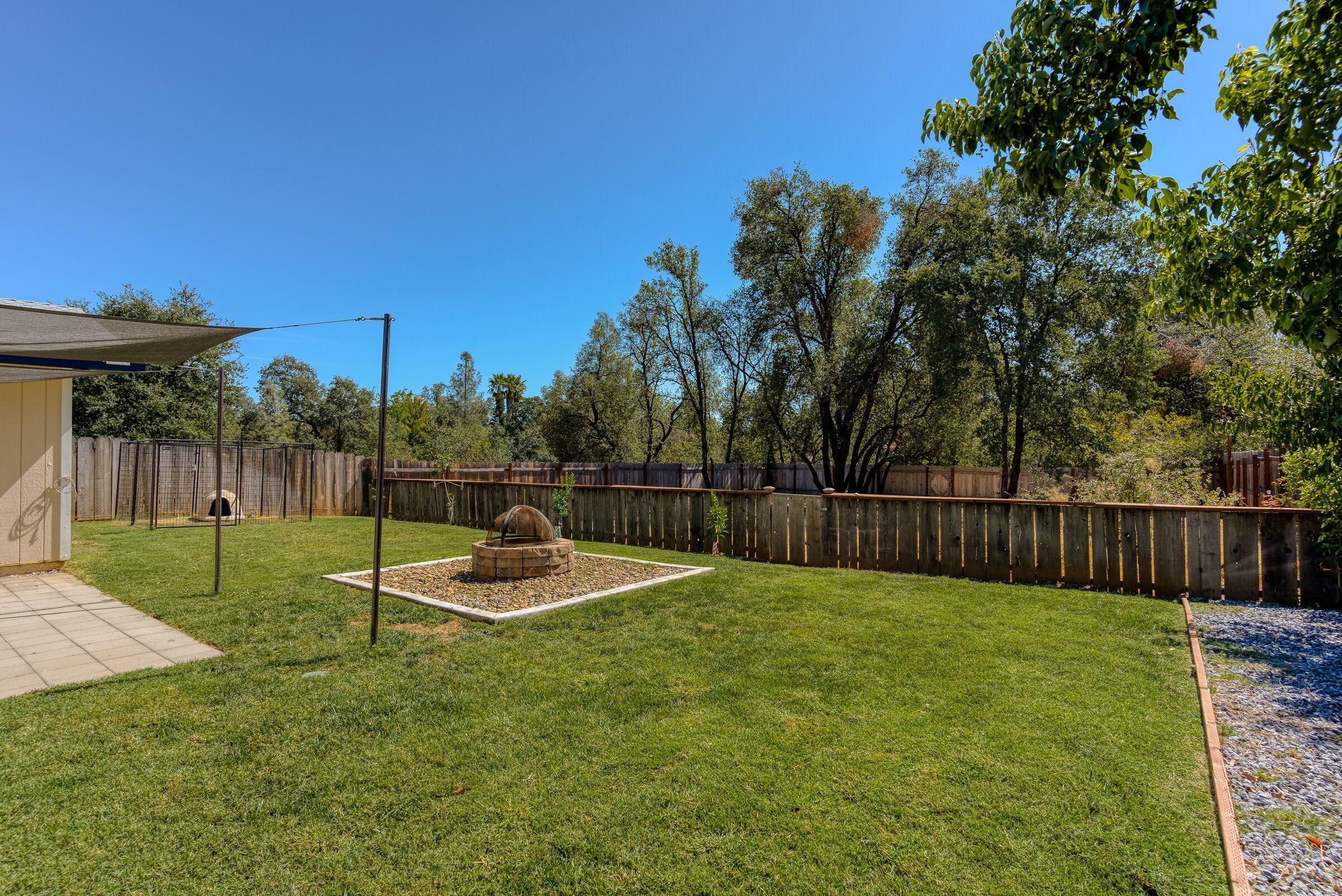 1209 Woodside Meadows Road Redding, CA 96002 - Photo 20 of 22 a view of a backyard with a small cabin and chair