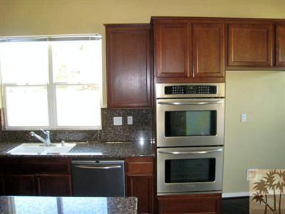 81908 Villa Reale Drive Indio, CA 92203 - Photo 6 of 25 a kitchen with granite countertop wooden cabinets stainless steel appliances and a window