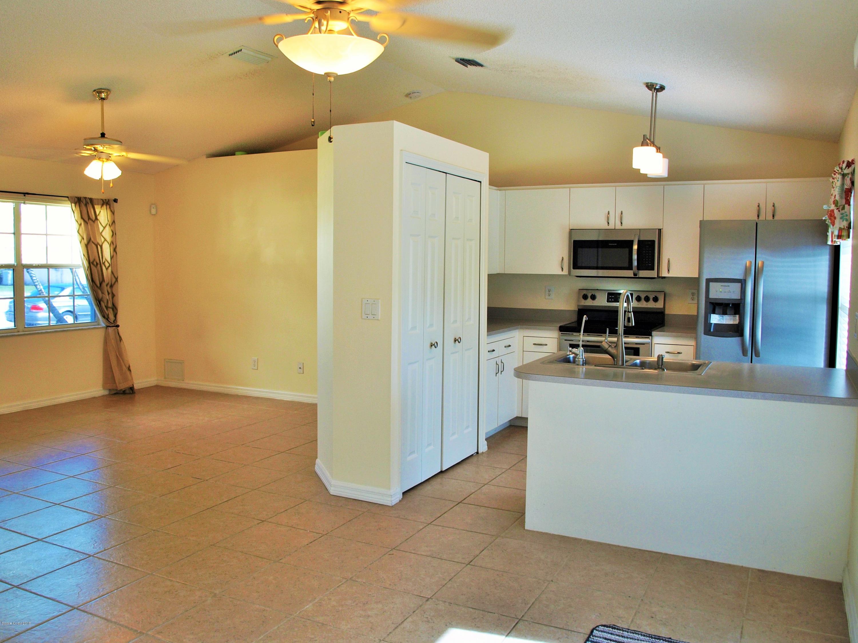 247 Crystal Lake Road Melbourne, FL 32901 - Photo 5 of 22 a view of a kitchen with kitchen island stainless steel appliances a stove a refrigerator and a view of living room