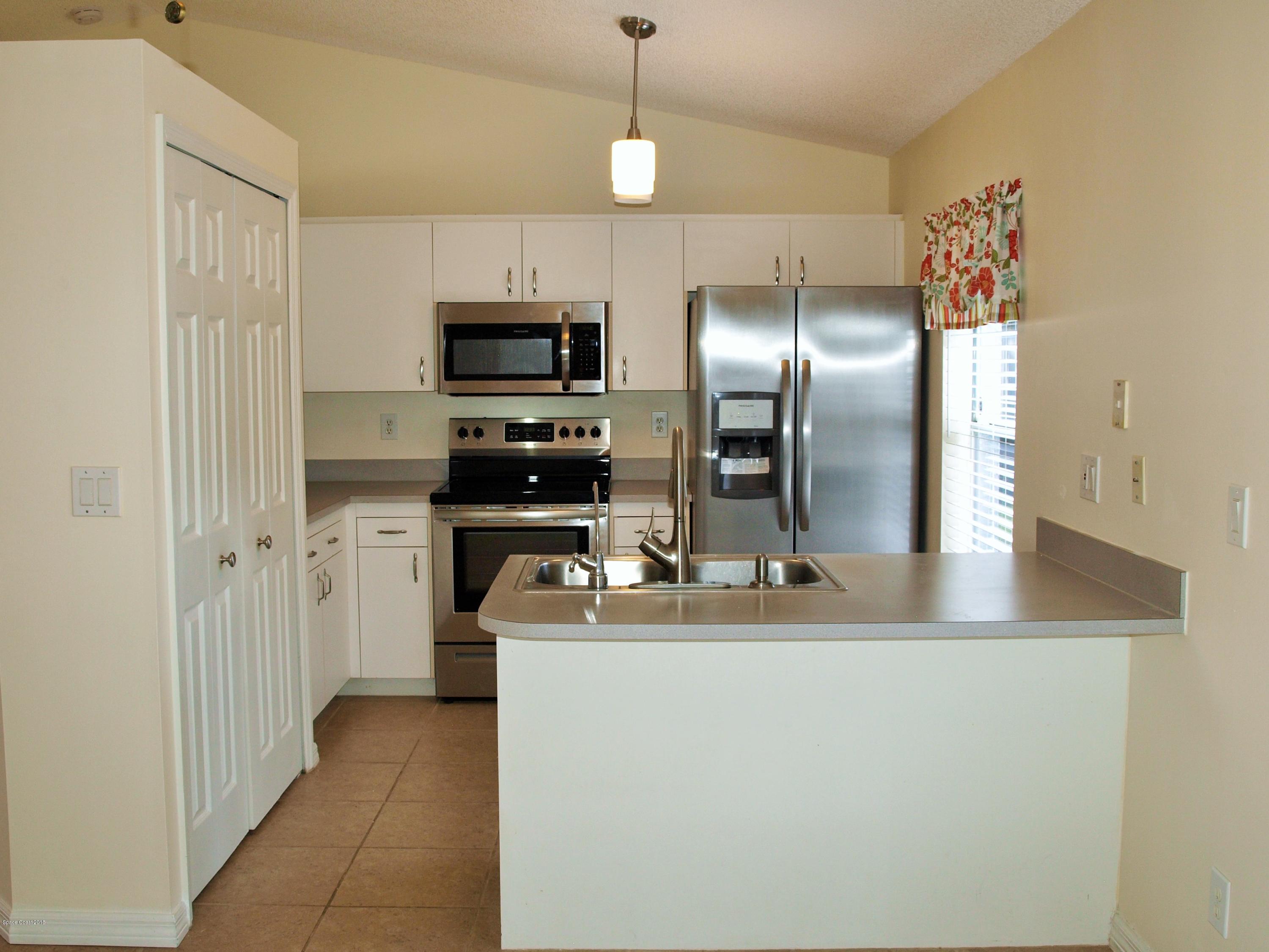 247 Crystal Lake Road Melbourne, FL 32901 - Photo 6 of 22 a kitchen with kitchen island a counter space a sink appliances and cabinets