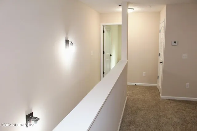 a view of a hallway with wooden floor and a bathroom