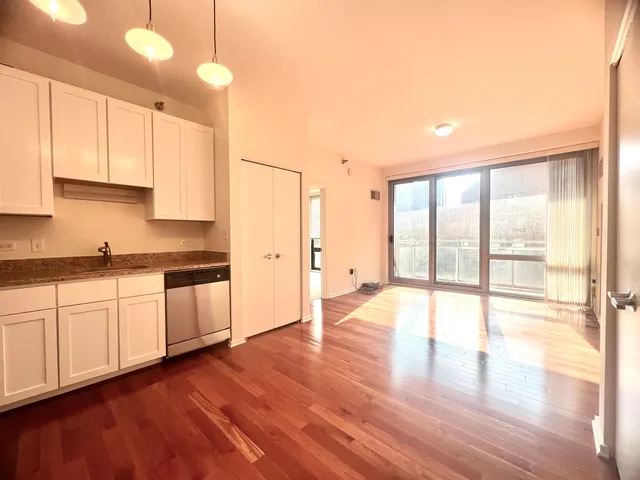 a open kitchen with granite countertop a stove top oven a sink and white cabinets with wooden floor