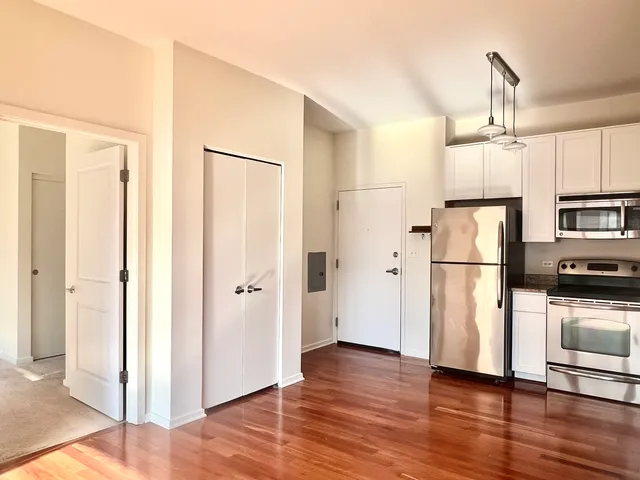 a kitchen with stainless steel appliances a refrigerator and a hard wood floor