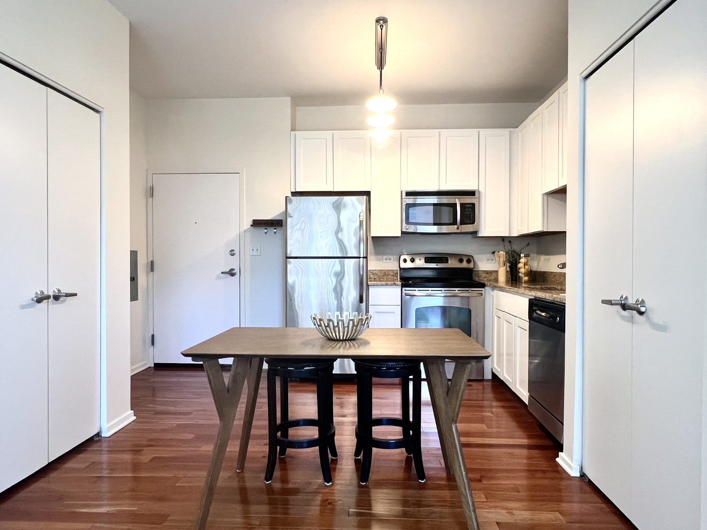 1 East 8th Street, Unit 307 Chicago, IL 60605 - Photo 6 of 24 a kitchen with stainless steel appliances a refrigerator a stove a microwave a dining table and chairs with wooden floor