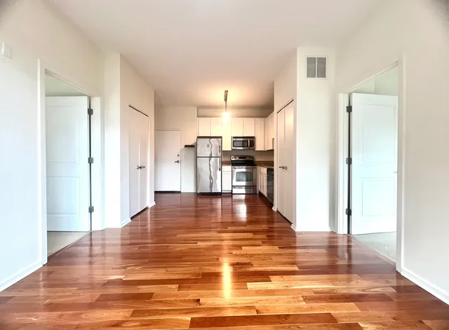 a view of a kitchen with kitchen island an empty room and wooden floor