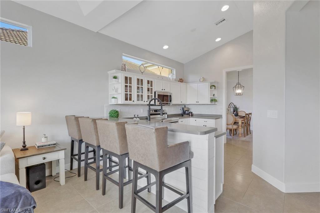 15464 Cortona Way Naples, FL 34120 - Photo 14 of 47 Kitchen with open shelves, a breakfast bar area, white cabinets, stainless steel microwave, and recessed lighting