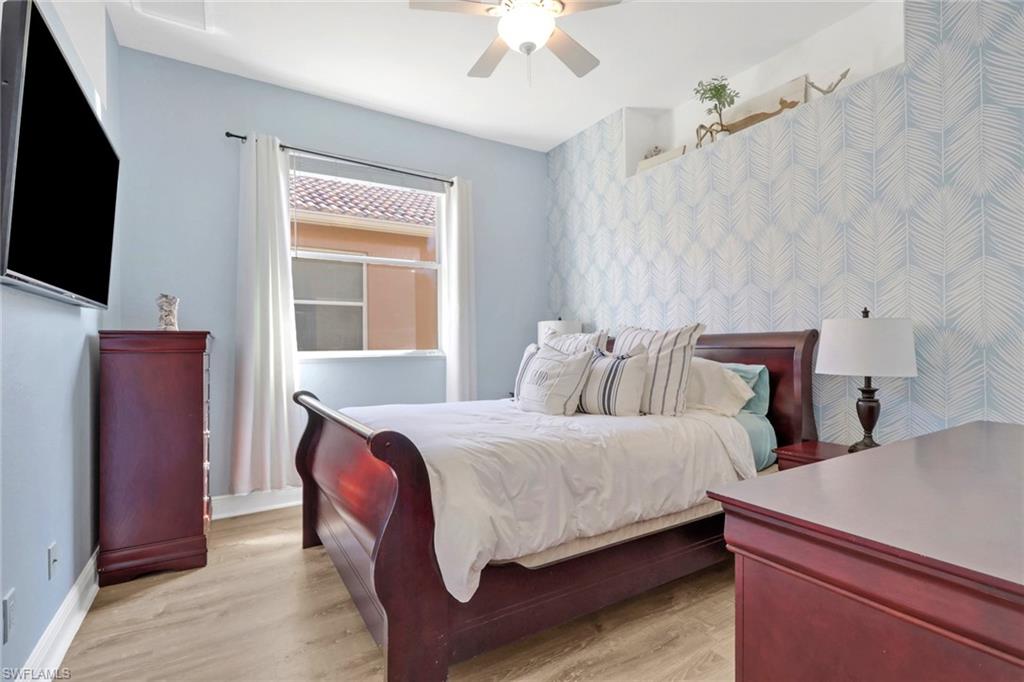 15464 Cortona Way Naples, FL 34120 - Photo 20 of 47 a bedroom with bed and tv with wooden floor
