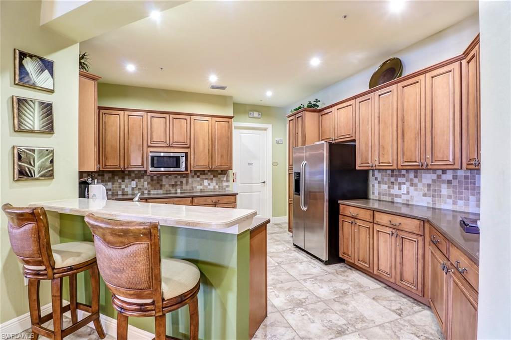 15464 Cortona Way Naples, FL 34120 - Photo 43 of 47 a kitchen with stainless steel appliances kitchen island granite countertop a refrigerator a stove top oven and a center island