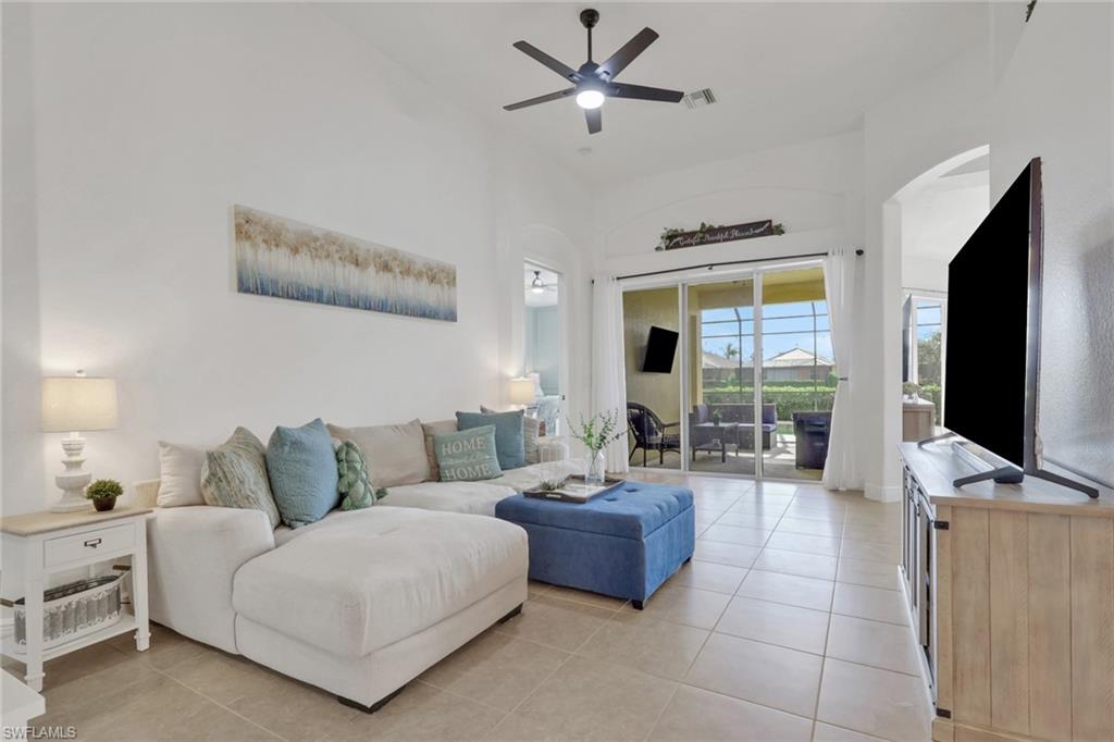 15464 Cortona Way Naples, FL 34120 - Photo 10 of 47 Living room with light tile patterned floors, arched walkways, a ceiling fan, and a towering ceiling