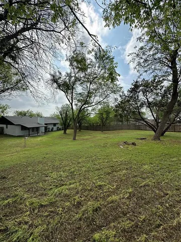 a view of a field with large trees