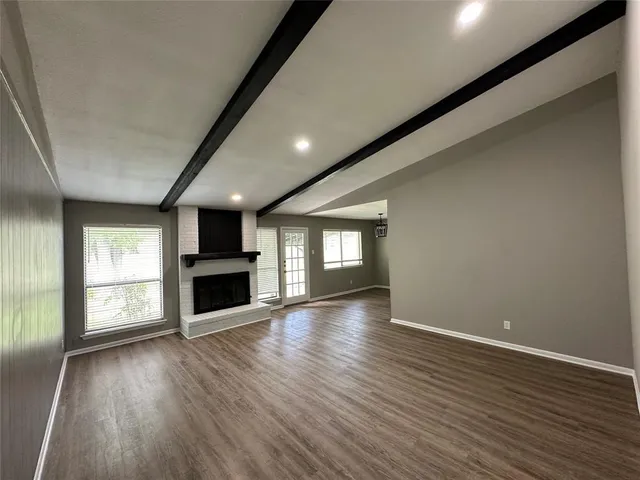 an empty room with wooden floor fireplace and windows