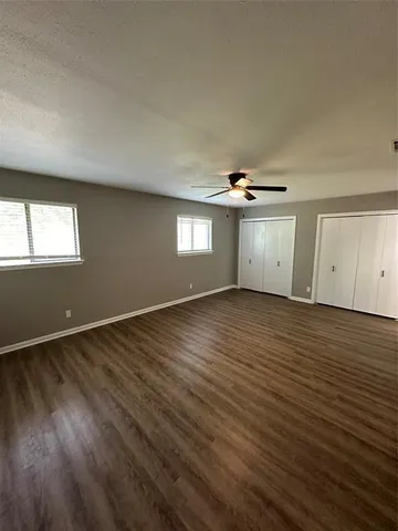 an empty room with wooden floor cabinet and windows