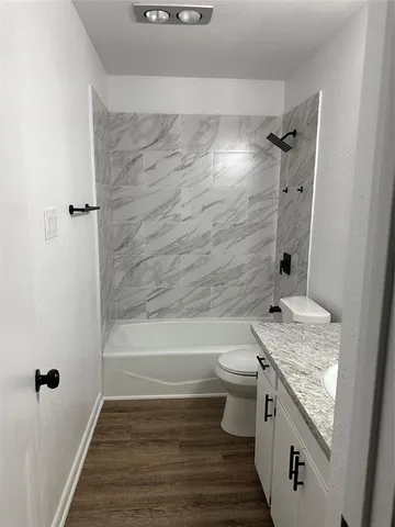 a bathroom with a granite countertop bathtub shower sink vanity and toilet