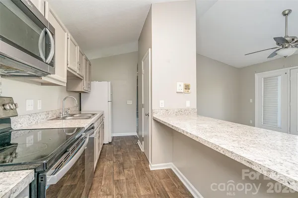 a kitchen with stainless steel appliances granite countertop a lot of counter space and wooden floor