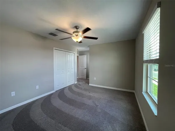 en empty room with windows and ceiling fan