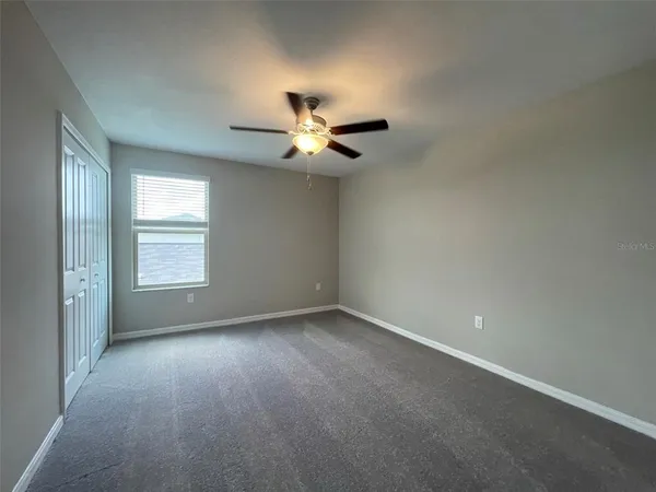 an empty room with a window and a ceiling fan