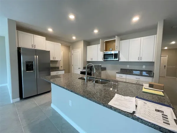 a large kitchen with granite countertop a large counter top stainless steel appliances and cabinets