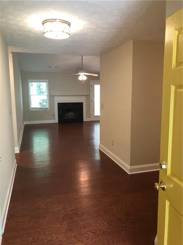 an empty room with wooden floor fireplace and windows