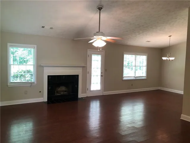 a view of an empty room with wooden floor fireplace and a window