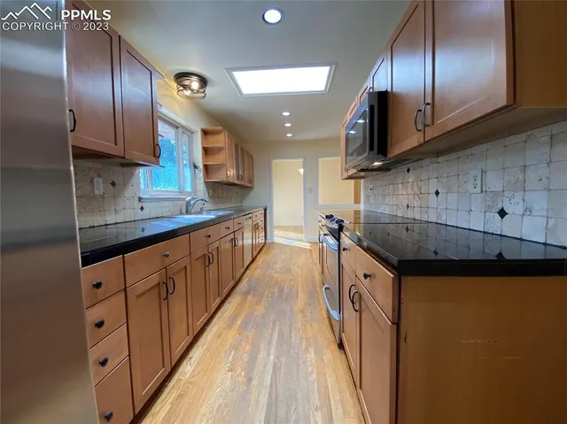 a kitchen with stainless steel appliances granite countertop a sink a stove and a wooden floors