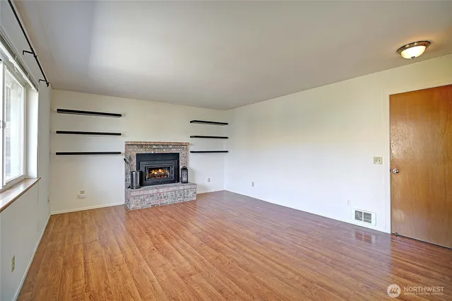 an empty room with wooden floor and fireplace