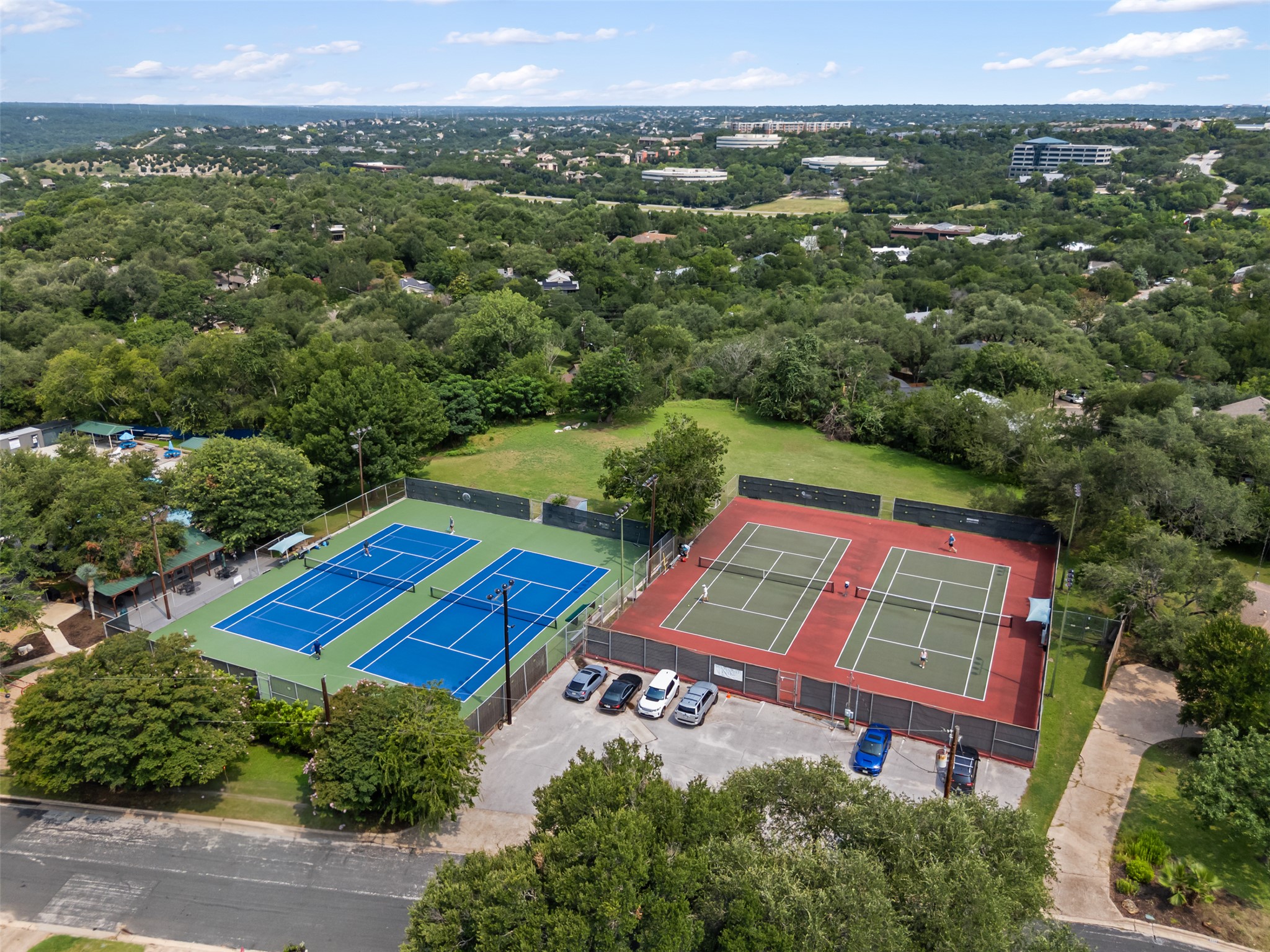 8900 Point W Drive Austin, TX 78759 - Photo 39 of 40 Two vibrant tennis courts offer recreational opportunities amidst a lush, treed landscape.