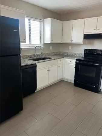 a kitchen with granite countertop white cabinets sink and stainless steel appliances