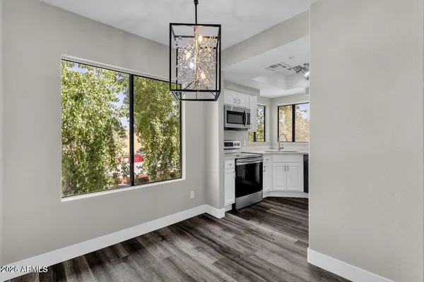 a kitchen with stove and white cabinets with wooden floor