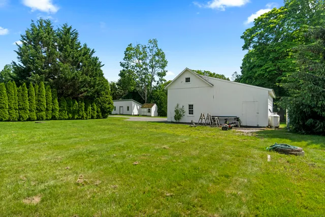 a view of a white house with a big yard and large trees