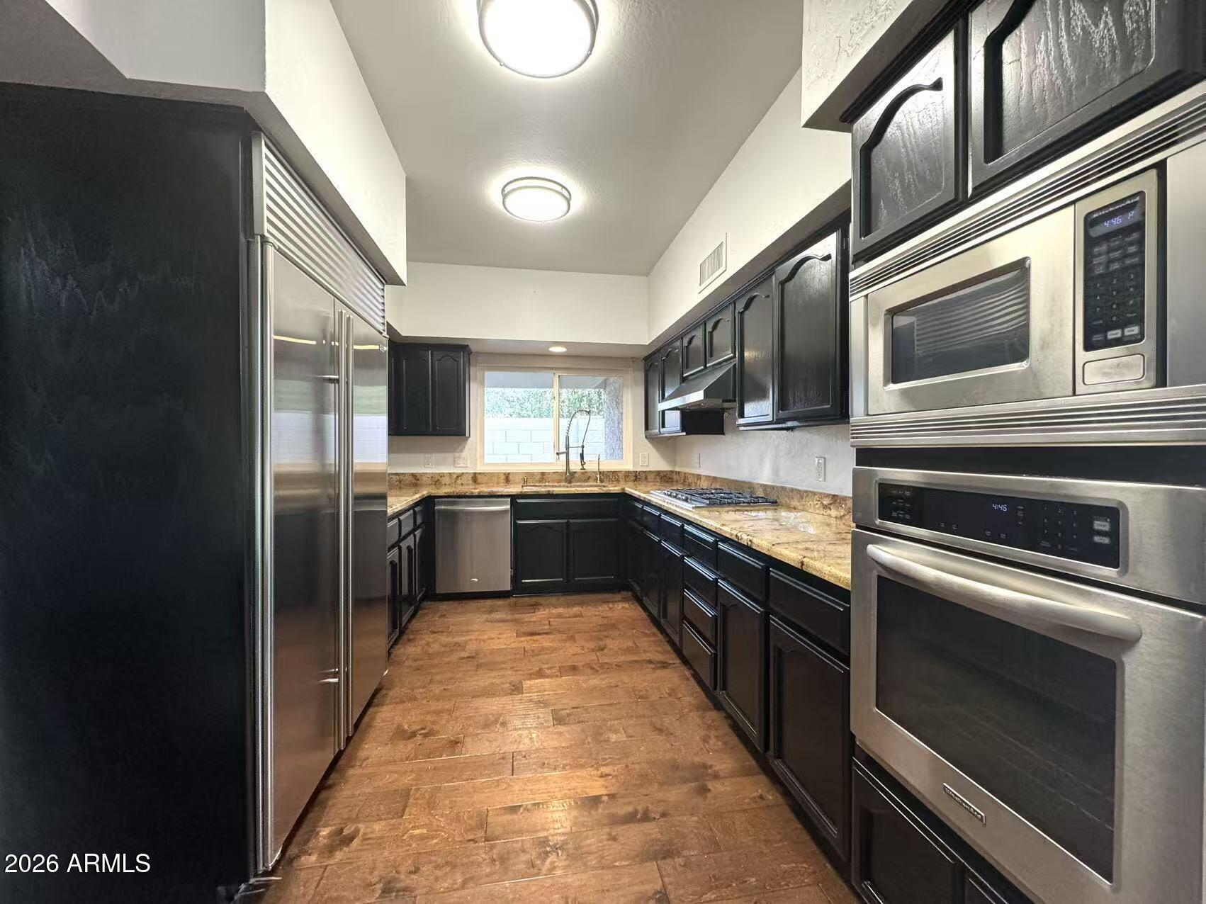 7330 East Griswold Road Scottsdale, AZ 85258 - Photo 14 of 16 a kitchen with stainless steel appliances kitchen island granite countertop a stove a sink and a refrigerator