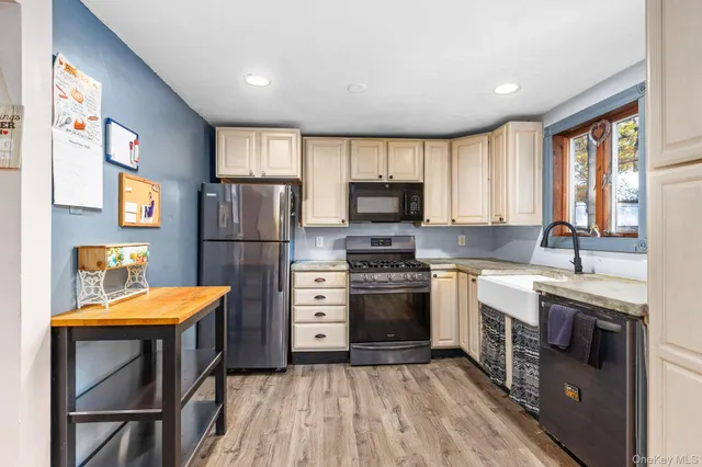 a kitchen with stainless steel appliances granite countertop a stove a sink dishwasher a refrigerator white cabinets and wooden floor