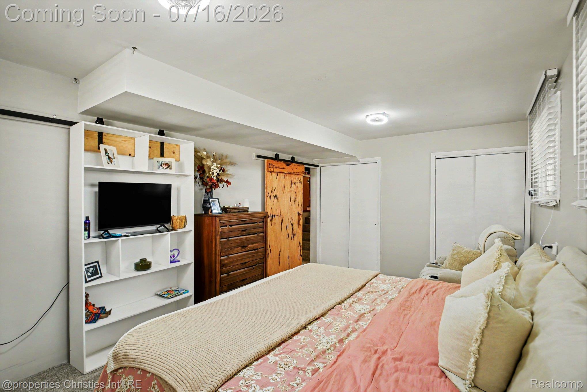 3304 Riverside Drive Port Huron, MI 48060 - Photo 10 of 26 Spacious room featuring a white built-in shelving unit, natural wood barn door, dual white sliding closet doors, and window blinds