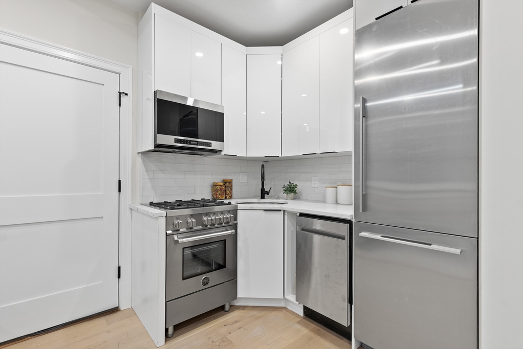 166 Salem Street, Unit A Boston, MA 02113 - Photo 5 of 16 a kitchen with white cabinets and stainless steel appliances