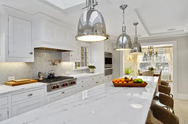 a kitchen with stainless steel appliances kitchen island granite countertop a stove a sink and a white cabinets
