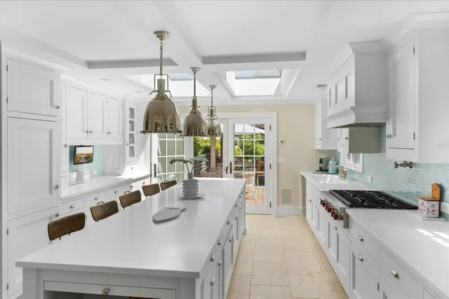 a kitchen with stainless steel appliances a sink a stove a refrigerator and white cabinets
