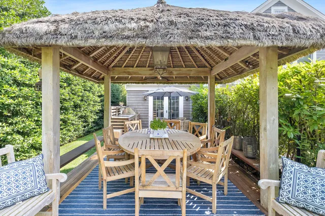 a view of a patio with table and chairs with wooden floor and fence
