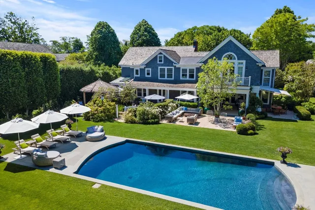 a view of a house with swimming pool lawn chairs and a yard