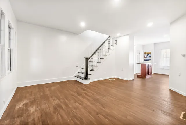 a view of empty room with wooden floor and stairs