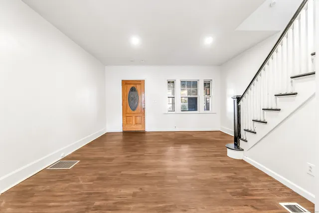 a view of an empty room with wooden floor and stairs
