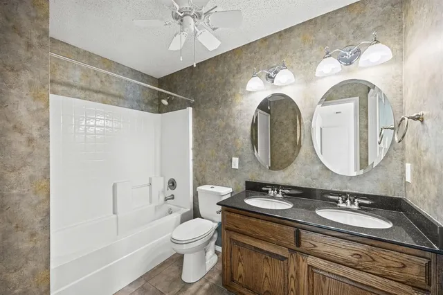 a bathroom with a granite countertop toilet sink and mirror