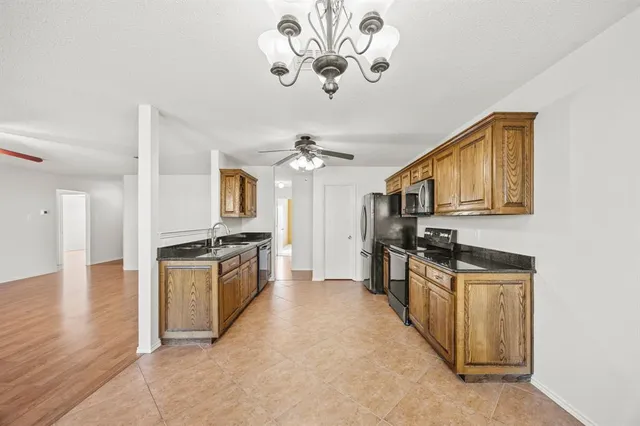 a kitchen with stainless steel appliances granite countertop a stove top oven a sink dishwasher and a refrigerator with wooden floor