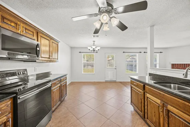 a kitchen with stainless steel appliances granite countertop a sink a stove top oven a chimney cabinets and a window