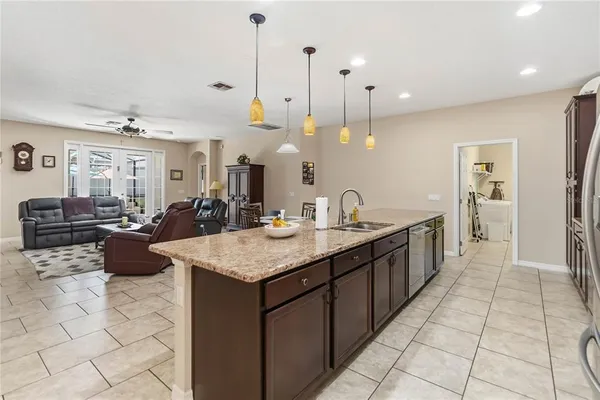 a large kitchen with kitchen island a counter top space a sink a counter space and a view of living room
