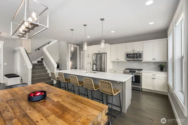 a kitchen with kitchen island stainless steel appliances a sink a stove a table and chairs