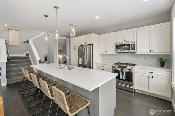 a kitchen with stainless steel appliances kitchen island a table chairs sink and cabinets