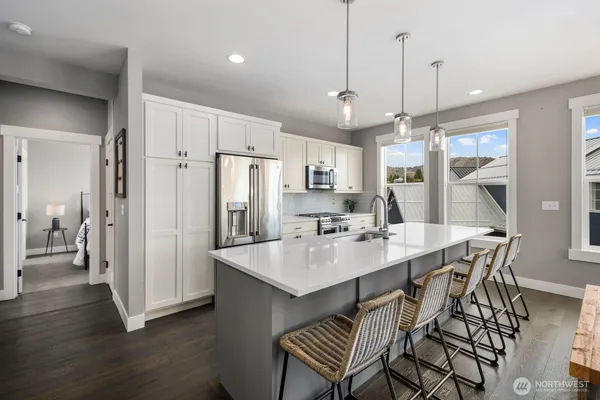 a kitchen with stainless steel appliances a dining table chairs and wooden floor