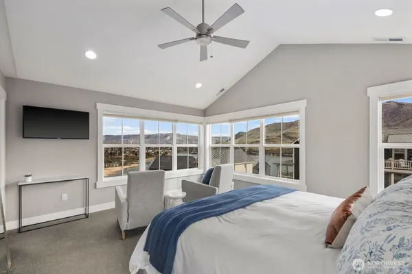 a bedroom with a large bed and a flat tv screen on dresser