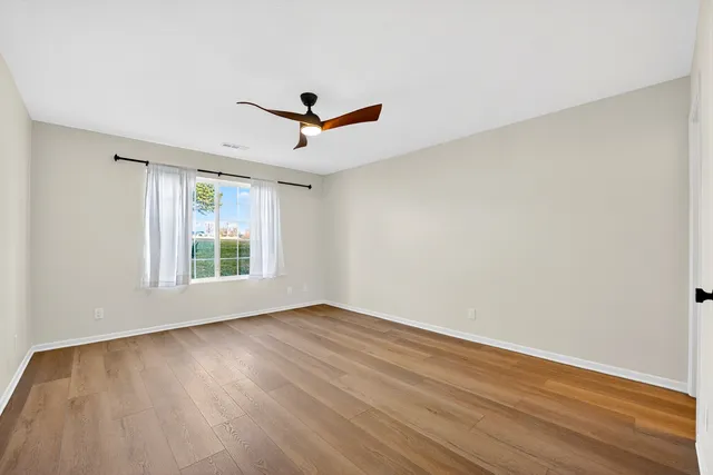 a view of empty room with wooden floor and fan